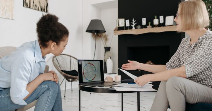 Two women discussing an astrology birth chart on a laptop